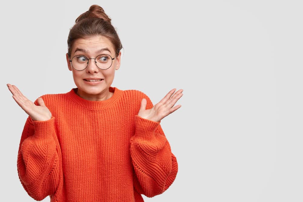 une femme en pull orange sur fond gris, ouvrir assurance vie luxembourg