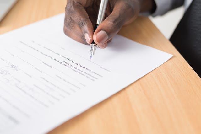 une main qui signe un contrat, meilleur contrat assurance vie luxembourg